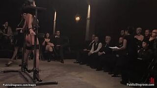 Bent over wooden stand on knees and bound in strappado brunette babe Cecilia Vega gets throat and pussy and ass fucked with dick on a stick in public